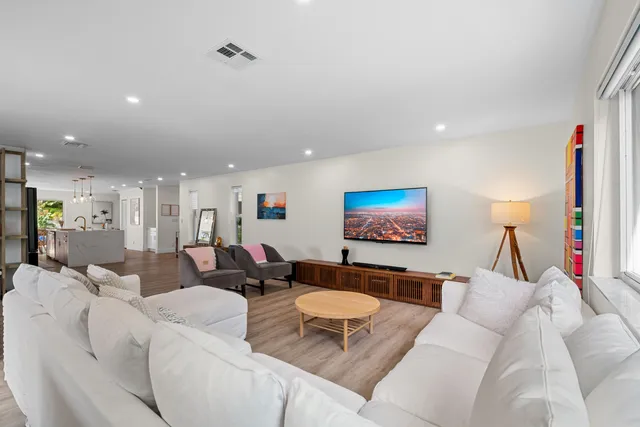 a spacious bedroom with a bed a dresser and large mirror