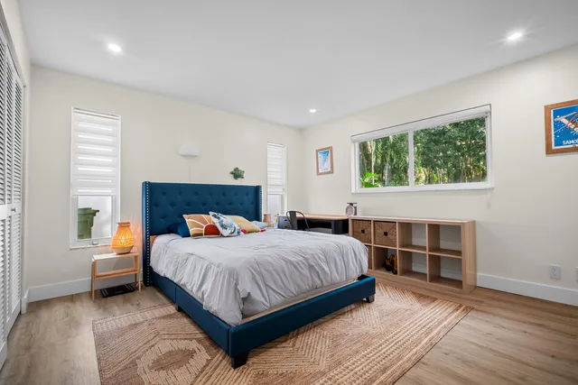 a living room with furniture large windows and wooden floor
