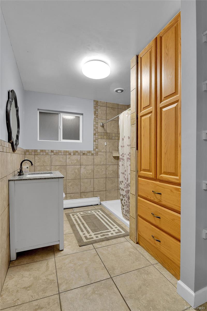 1632 Kiowa-Bennett Road Bennett, CO 80102 - Photo 12 of 42 a bathroom with a granite countertop sink a mirror and a shower