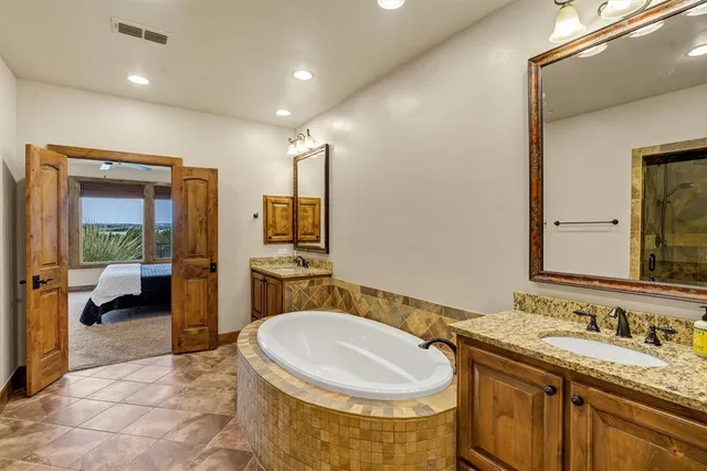 a spacious bathroom with a granite countertop sink mirror and bathtub