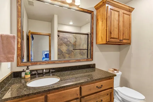 a bathroom with a granite countertop sink a mirror and a toilet