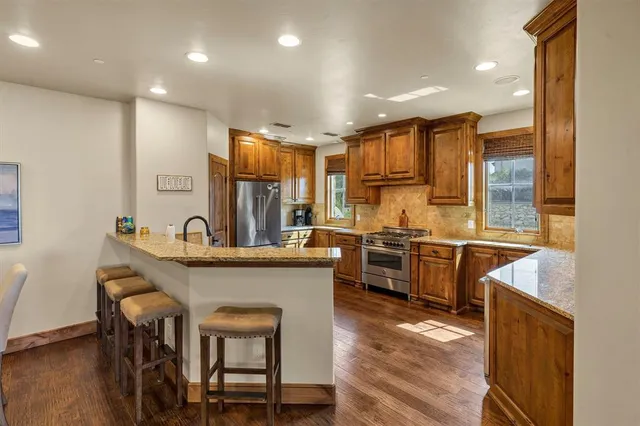 a kitchen with stainless steel appliances a sink a stove a refrigerator cabinets and wooden floor