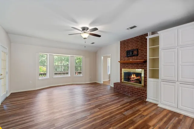 an empty room with wooden floor fireplace and windows