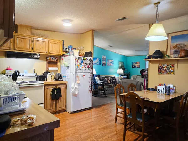 a kitchen with a refrigerator a stove a sink dishwasher and wooden cabinets with wooden floor