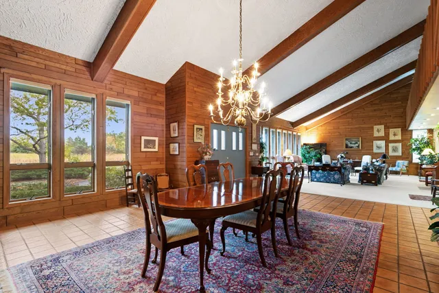 a dining room with furniture a rug a flat screen tv and a chandelier