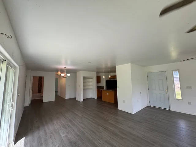 a view of a big room with wooden floor and a kitchen