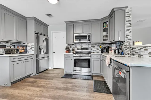 a kitchen with cabinets stainless steel appliances and sink