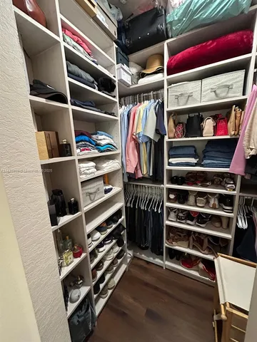 a view of walk in closet with clothes and shoes