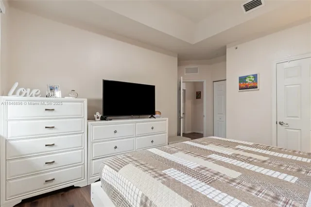 a bedroom with a bed and a flat screen tv in white walls