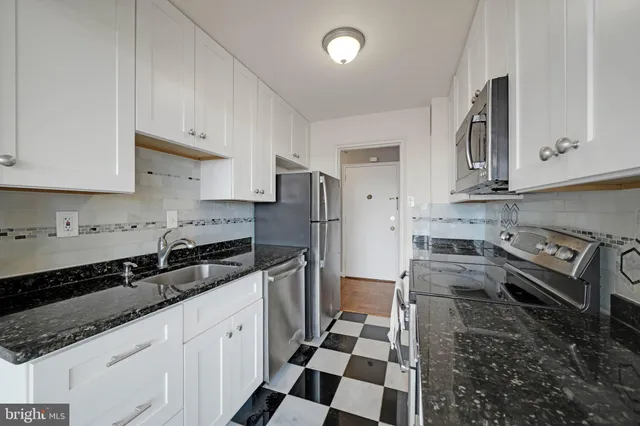a kitchen with stainless steel appliances granite countertop a sink stove refrigerator and cabinets