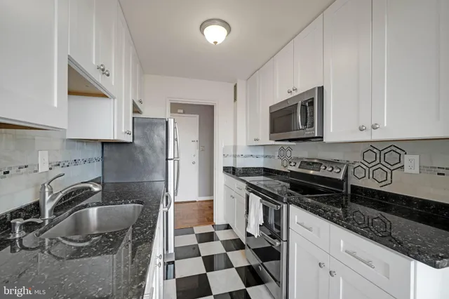 a kitchen with granite countertop a sink a stove a refrigerator and cabinets