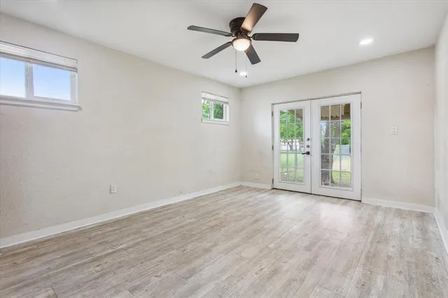 an empty room with wooden floor and windows