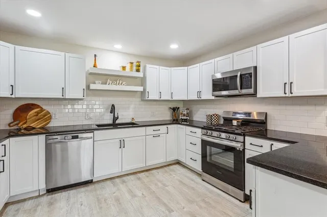 a kitchen with stainless steel appliances granite countertop a stove sink and cabinets