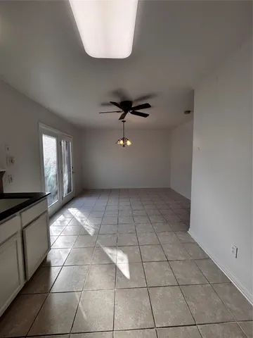 a view of an empty room with a chandelier fan