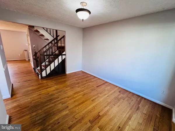 a view of an empty room with wooden floor and stairs
