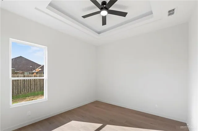 an empty room with a window and a chandelier fan