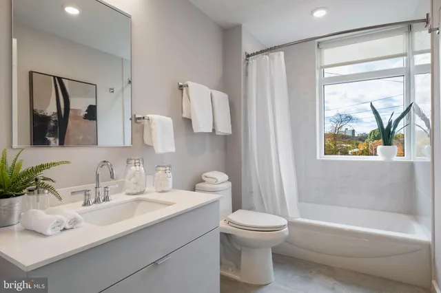 a bathroom with a bathtub shower sink vanity and toilet