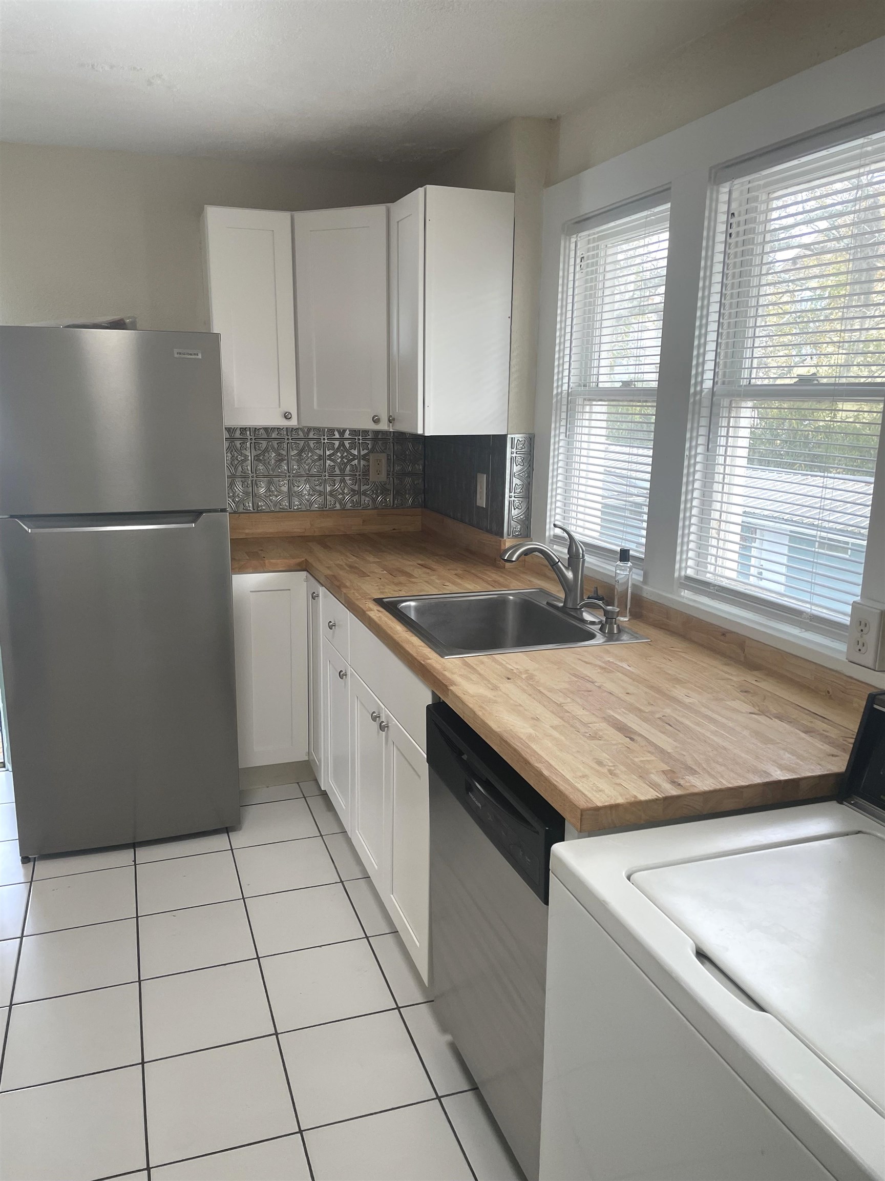 143 A Riberia Street St. Augustine, FL 32084 - Photo 3 of 11 Kitchen with washer / dryer, appliances with stainless steel finishes, white cabinetry, wooden counters, and light tile patterned floors