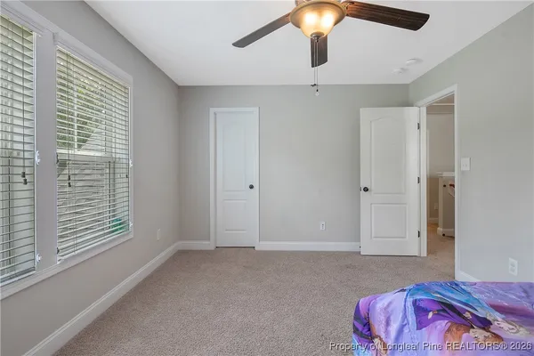 a spacious bedroom with a bed and a chandelier fan