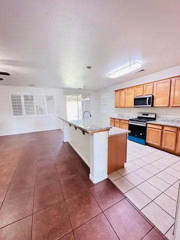 a large kitchen with stainless steel appliances a stove a sink a counter top space and cabinets
