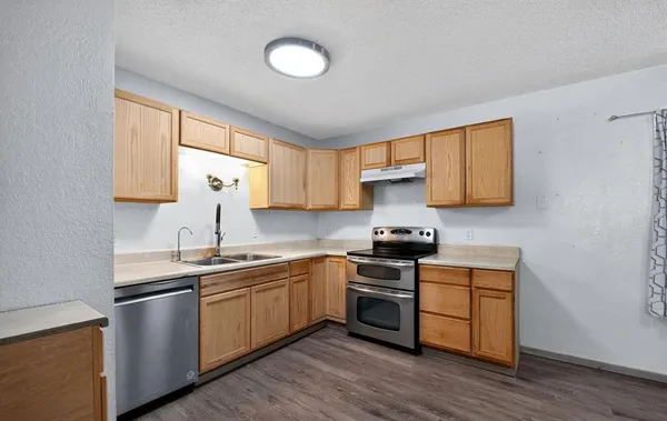 a kitchen with stainless steel appliances granite countertop a sink a stove a refrigerator cabinets and a window