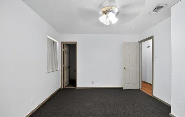 an empty room with a chandelier fan and closet