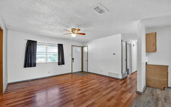 a view of an empty room with wooden floor and a window