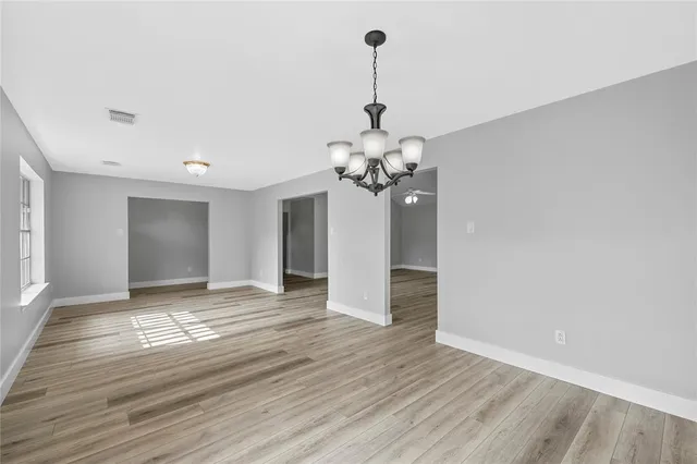 a view of a livingroom with a chandelier and wooden floor