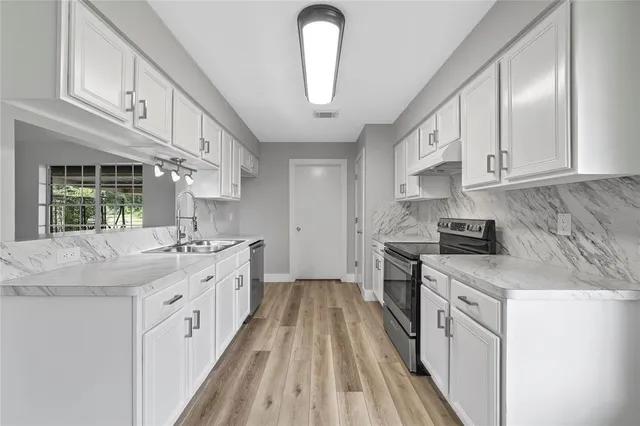 a kitchen with stainless steel appliances granite countertop a stove a sink and a refrigerator