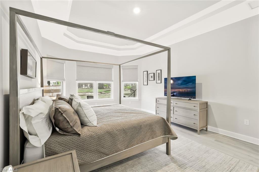 15804 Derna Street Naples, FL 34114 - Photo 13 of 28 Bedroom featuring light wood finished floors and a tray ceiling