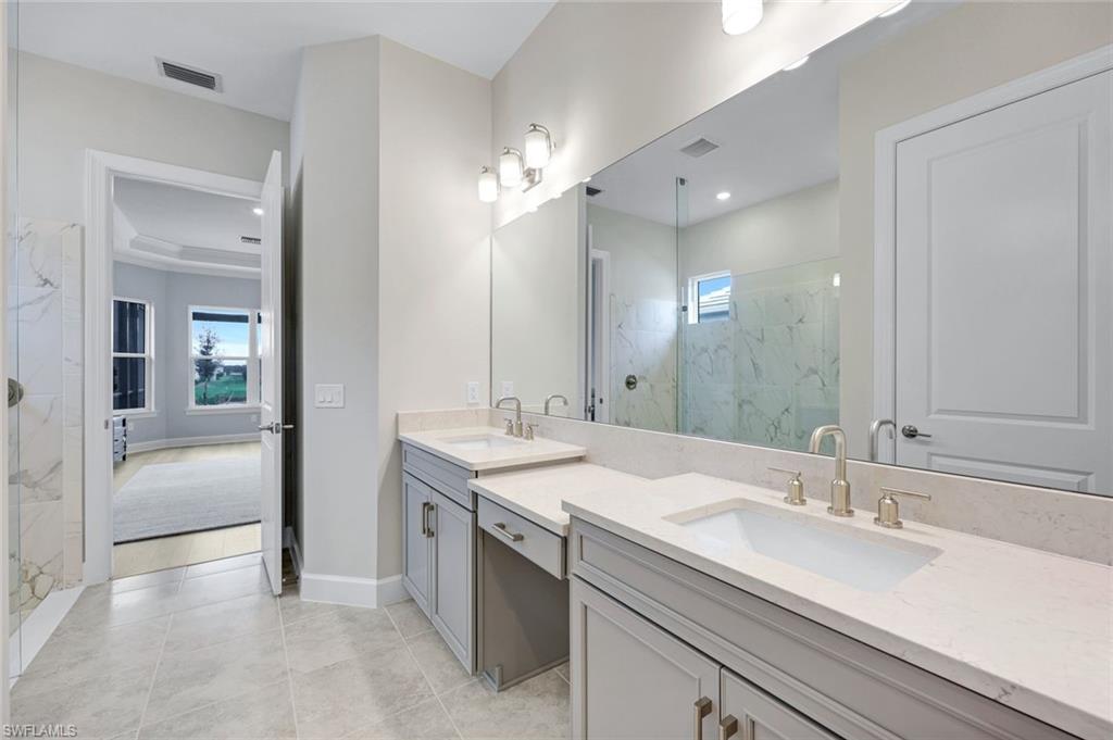 15804 Derna Street Naples, FL 34114 - Photo 14 of 28 Bathroom featuring a marble finish shower, double vanity, healthy amount of natural light, and light tile patterned flooring