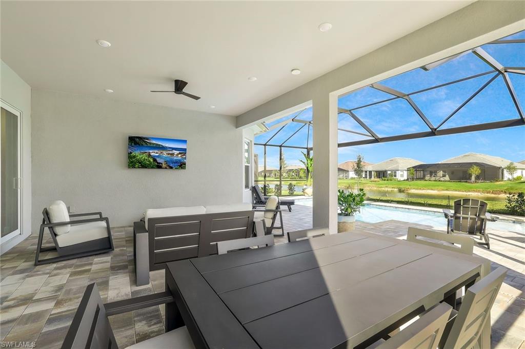 15804 Derna Street Naples, FL 34114 - Photo 21 of 28 View of patio / terrace with a sunroom, outdoor dining area, an outdoor pool, and an outdoor hangout area