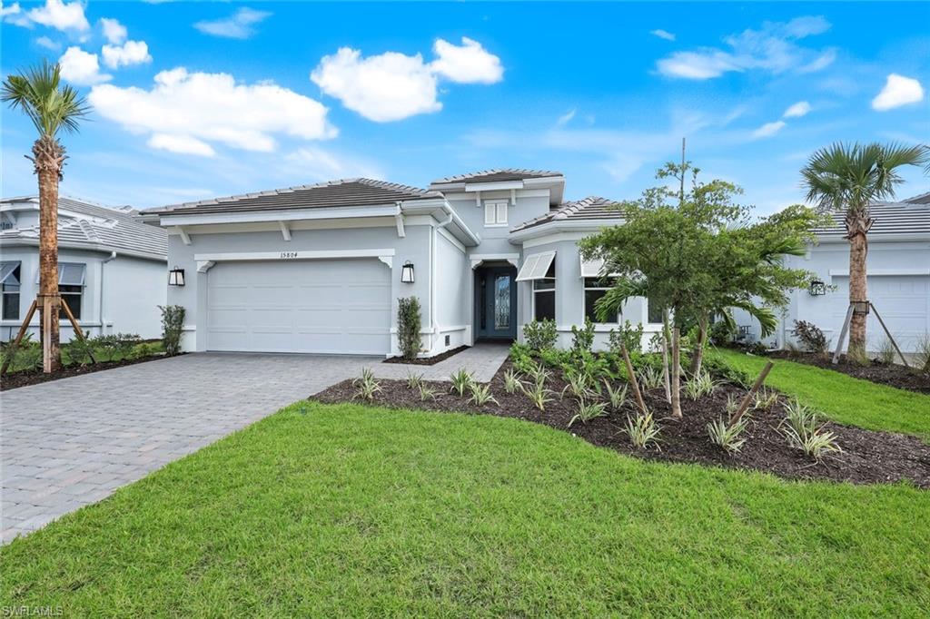15804 Derna Street Naples, FL 34114 - Photo 3 of 28 View of front of home with decorative driveway, stucco siding, and a front yard