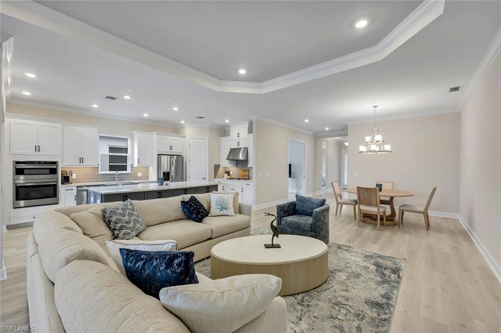 15804 Derna Street Naples, FL 34114 - Photo 4 of 22 Living area with recessed lighting, ornamental molding, a chandelier, light wood-style floors, and a tray ceiling