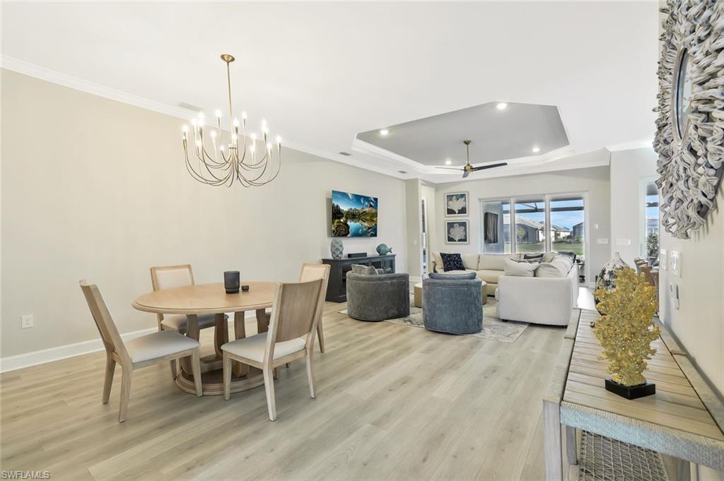 15804 Derna Street Naples, FL 34114 - Photo 7 of 28 Dining room with crown molding, ceiling fan, light wood-style floors, a raised ceiling, and a chandelier