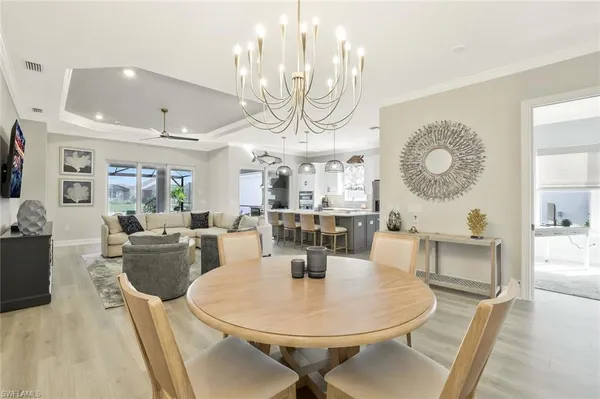 a dining room with wooden floor a chandelier a wooden table and chairs
