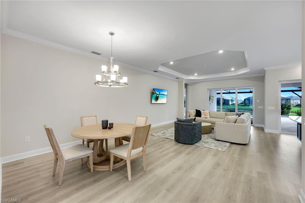 15804 Derna Street Naples, FL 34114 - Photo 8 of 22 Dining room featuring crown molding, light wood-style flooring, a tray ceiling, and a chandelier