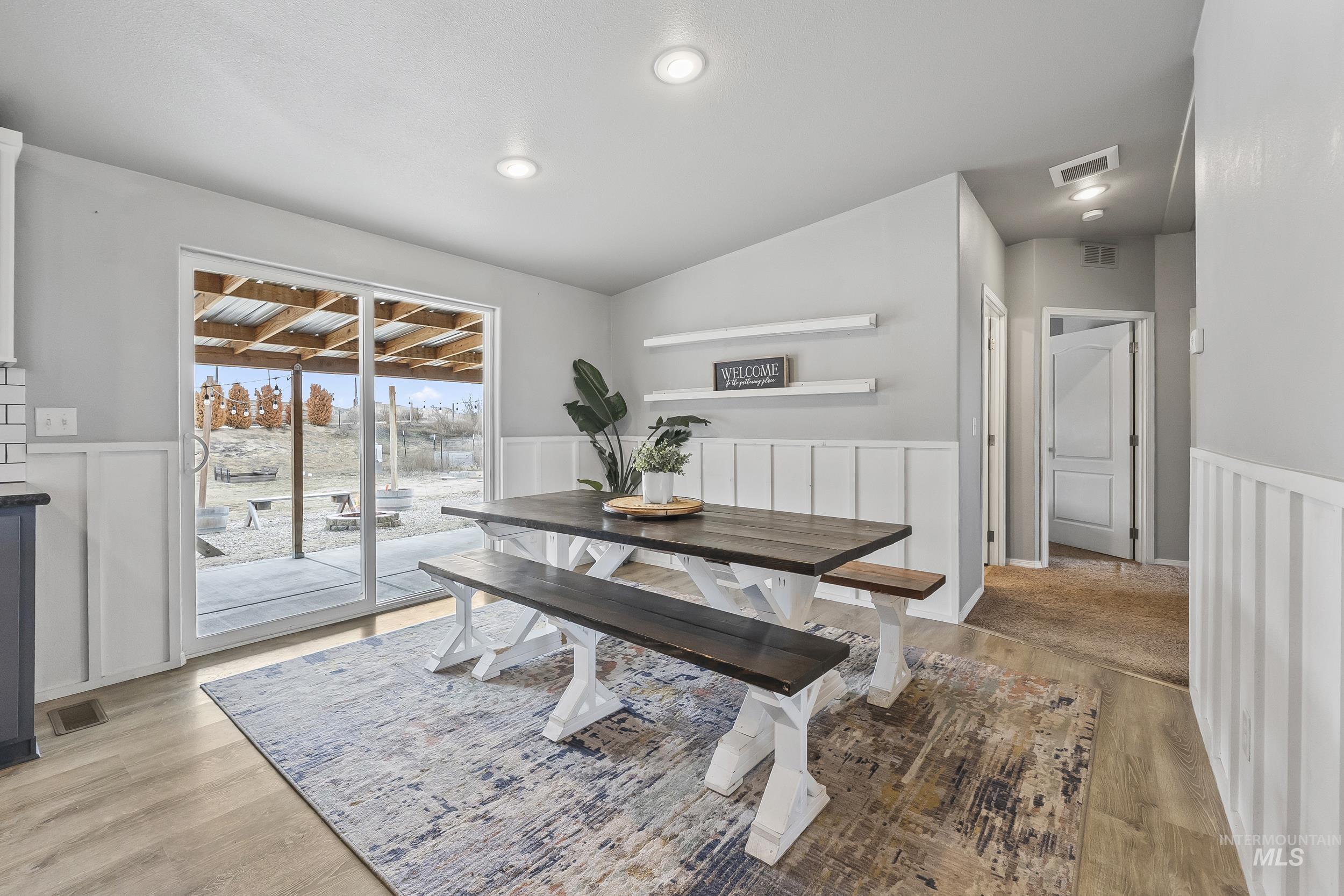 12944 Goodson Road Caldwell, ID 83607 - Photo 14 of 47 Dining room featuring a wainscoted wall, light wood-style flooring, a decorative wall, and vaulted ceiling