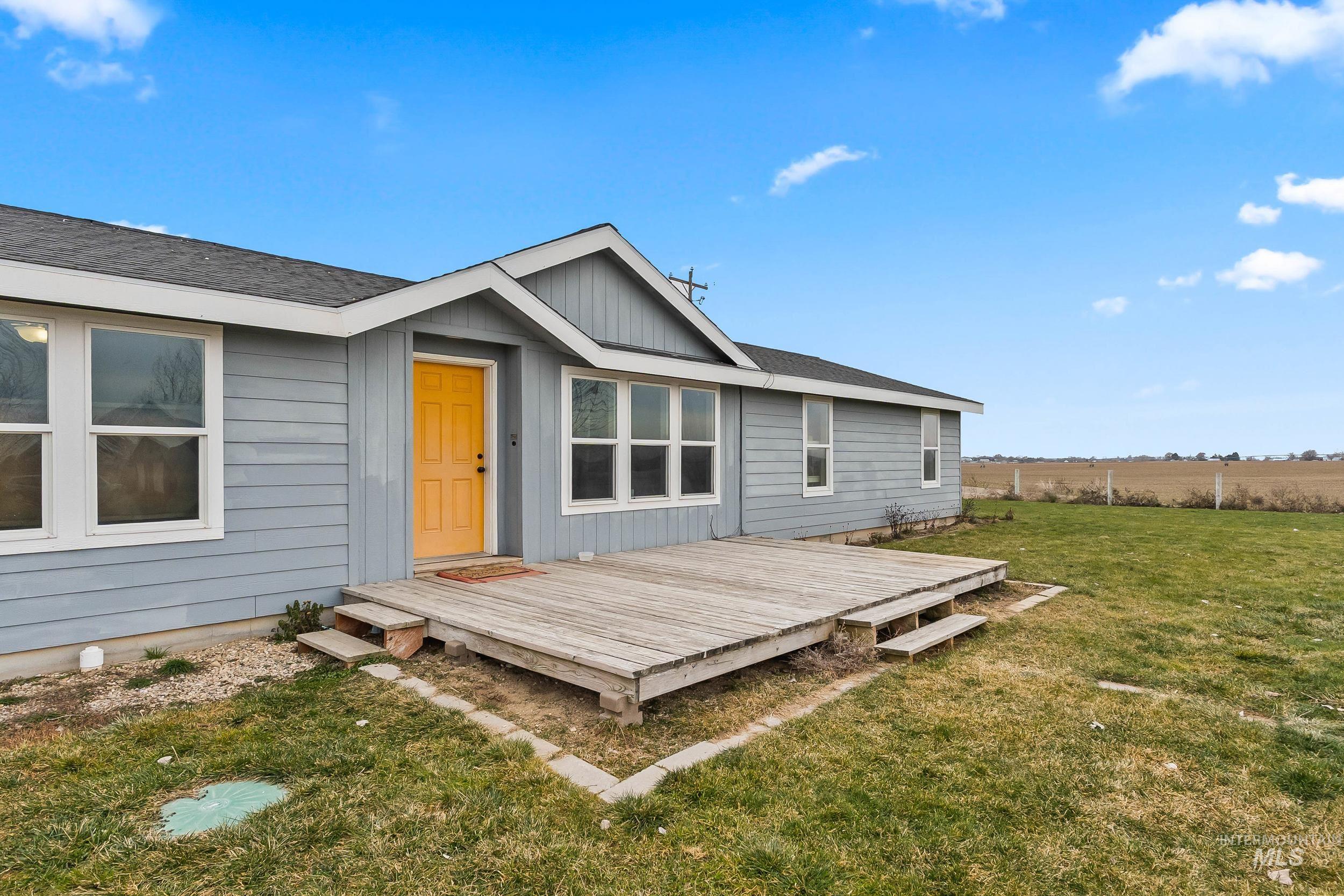 12944 Goodson Road Caldwell, ID 83607 - Photo 4 of 47 Back of house featuring a wooden deck, a yard, and roof with shingles