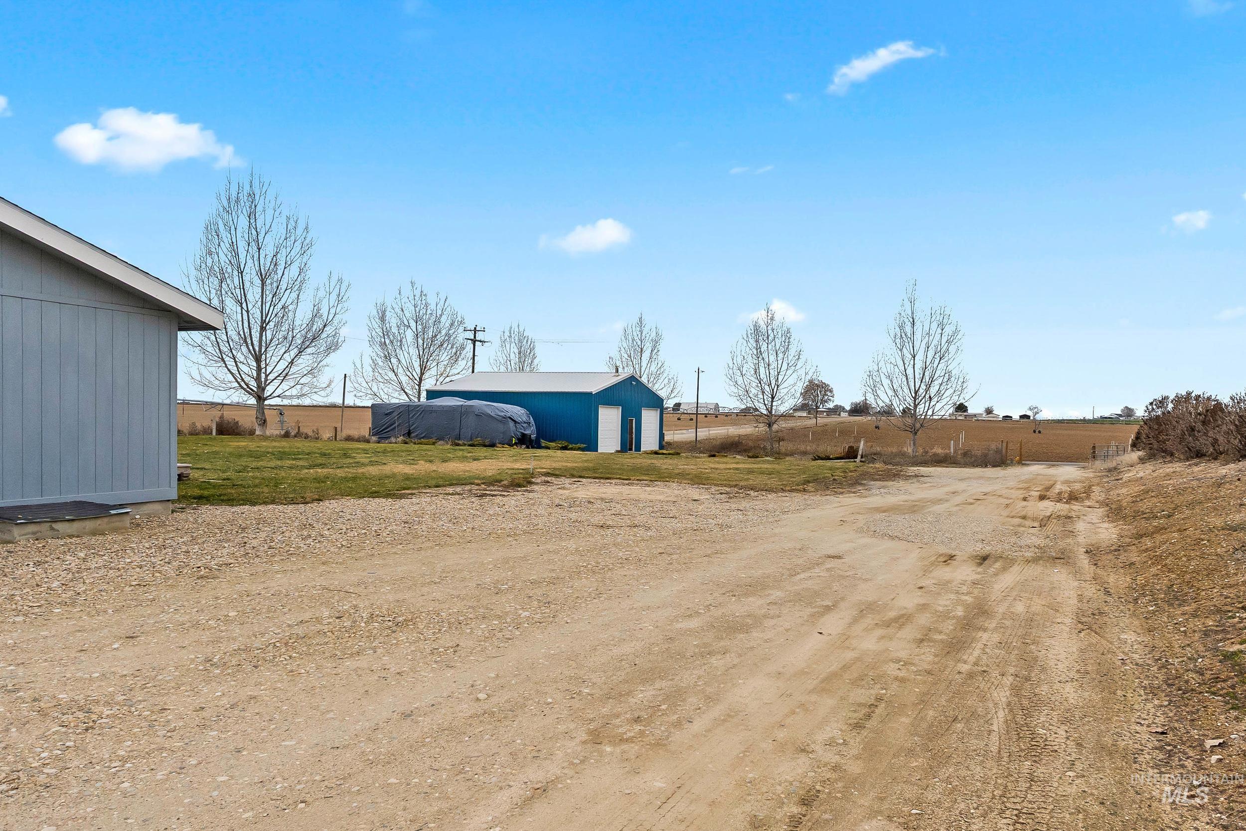 12944 Goodson Road Caldwell, ID 83607 - Photo 39 of 47 View of yard featuring an outdoor structure, driveway, a garage, and an outbuilding