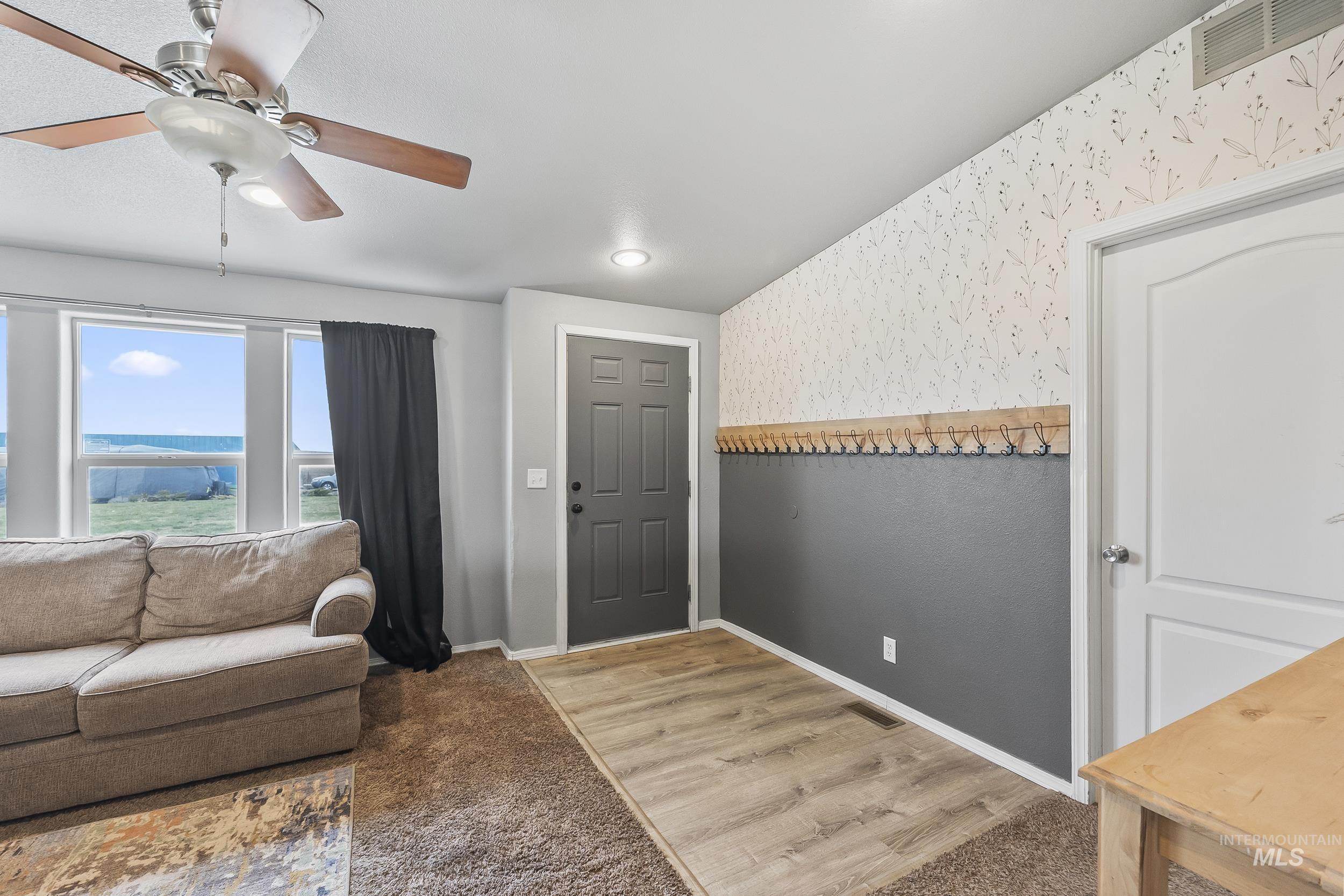 12944 Goodson Road Caldwell, ID 83607 - Photo 5 of 47 Living area featuring light carpet, light wood-style flooring, and a ceiling fan