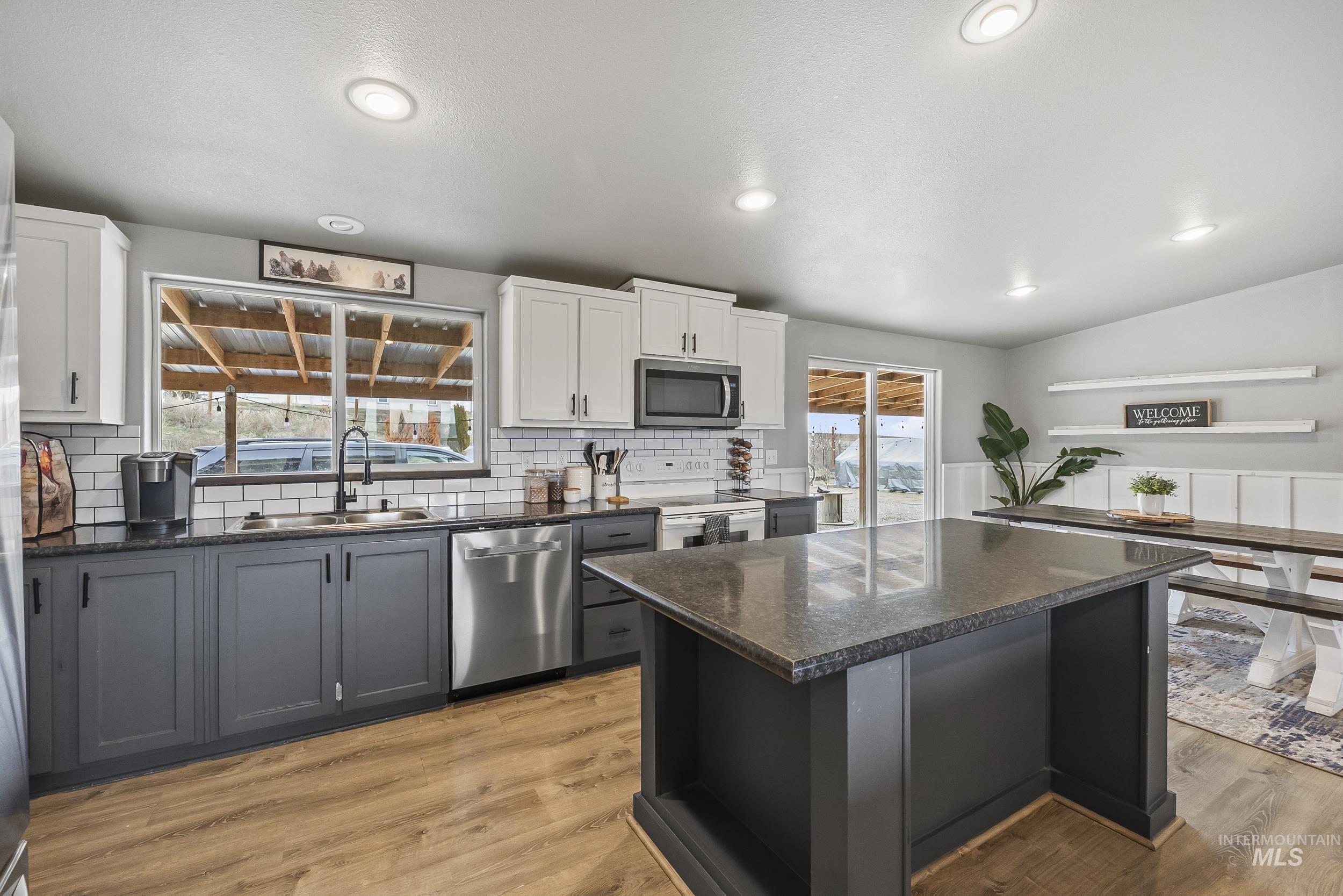 12944 Goodson Road Caldwell, ID 83607 - Photo 10 of 47 Kitchen featuring gray cabinets, light wood-type flooring, white cabinetry, stainless steel appliances, and vaulted ceiling
