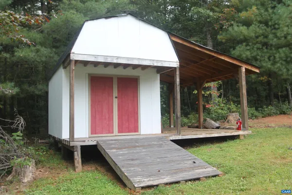 a view of a wooden house with a yard chairs and floor to ceiling window