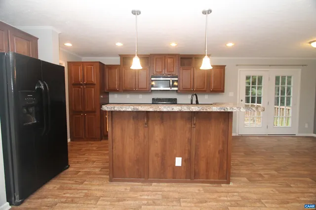 a kitchen with kitchen island granite countertop a refrigerator a sink and a stove