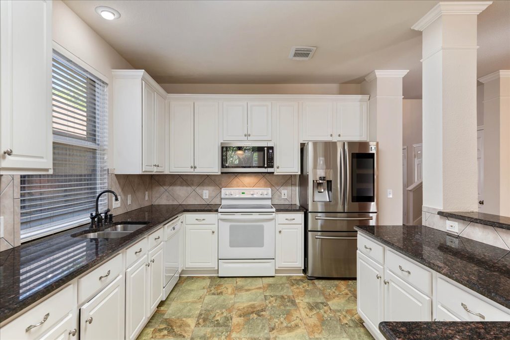 10937 Colonel Winn Loop Austin, TX 78748 - Photo 21 of 36 a kitchen with granite countertop a refrigerator sink and cabinets