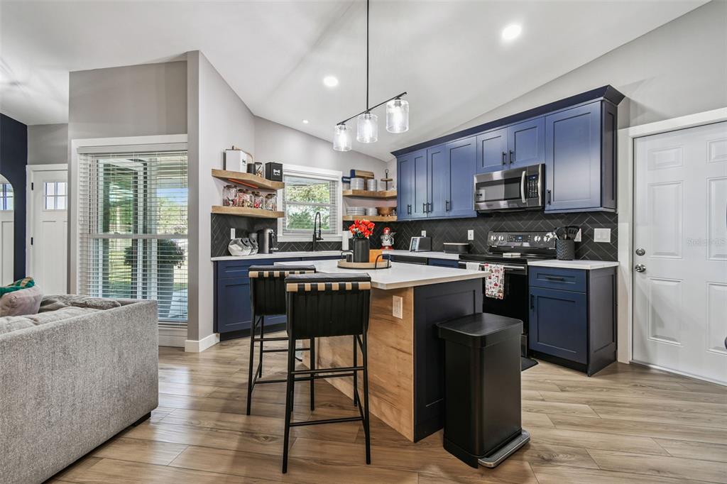 1729 Lakecrest Avenue Brandon, FL 33510 - Photo 11 of 51 a kitchen with stainless steel appliances granite countertop a refrigerator a stove a sink a dining table and chairs with wooden floor