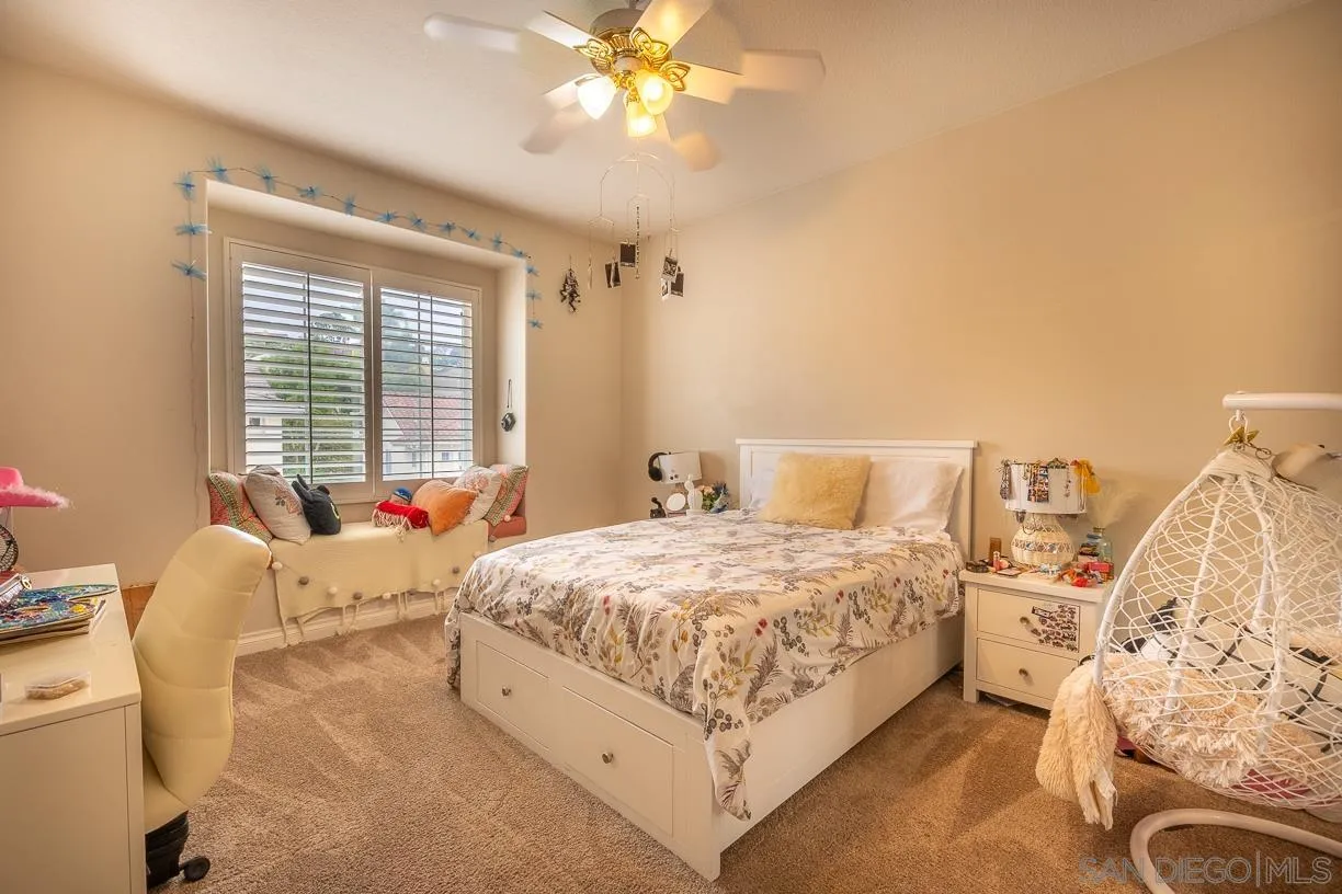 2435 Ridgegate Row La Jolla, CA 92037 - Photo 21 of 30 a spacious bedroom with a bed and a chandelier