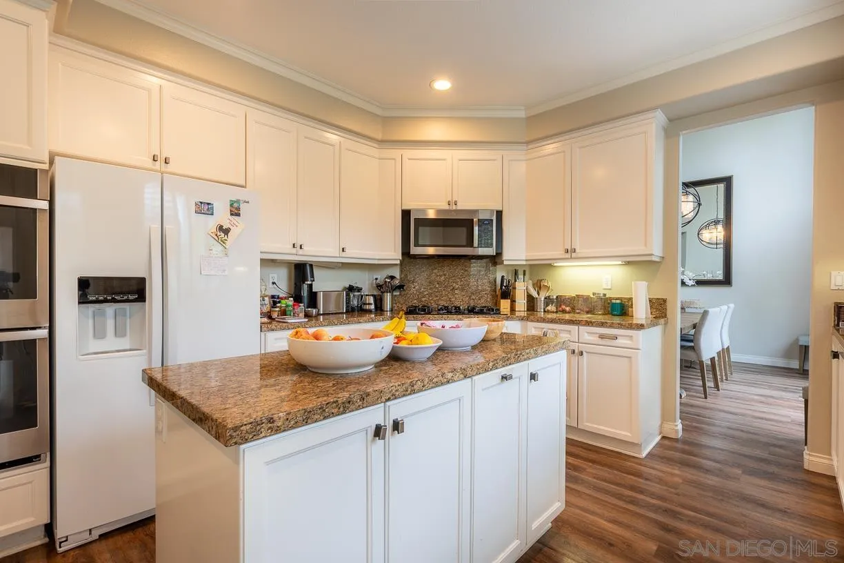 2435 Ridgegate Row La Jolla, CA 92037 - Photo 7 of 30 a kitchen with a refrigerator a stove a sink and white cabinets