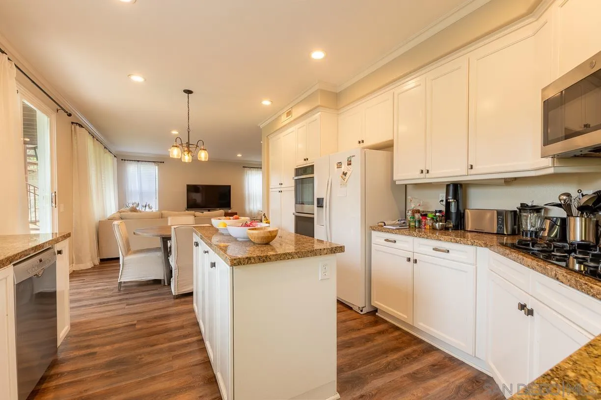 2435 Ridgegate Row La Jolla, CA 92037 - Photo 8 of 30 a kitchen with stainless steel appliances a stove a sink dishwasher a refrigerator white cabinets and wooden floor