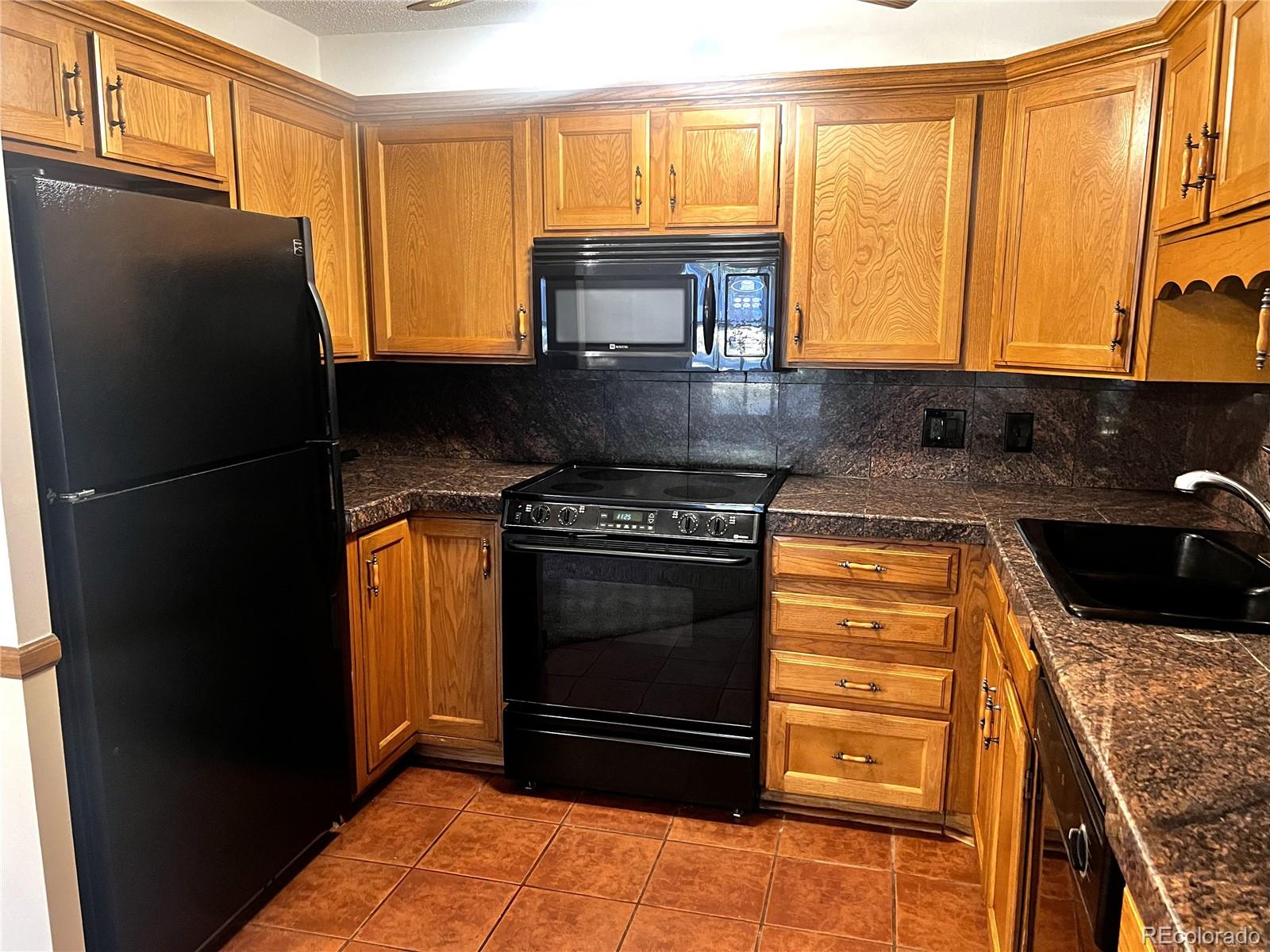 3082 South Wheeling Way, Unit 104 Aurora, CO 80014 - Photo 1 of 27 a kitchen with granite countertop a refrigerator stove and cabinets
